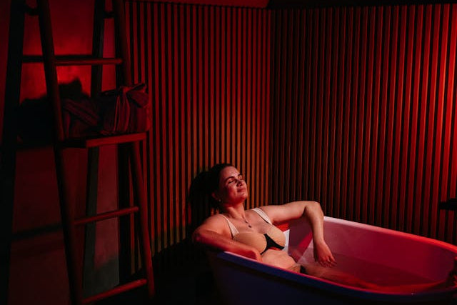 Person in a bathtub with red lighting in a dimly lit room